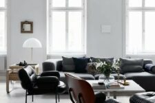 a black and white Scandinavian living room with plenty of natural light, black seating furniture, a white coffee table and a white paper lamp