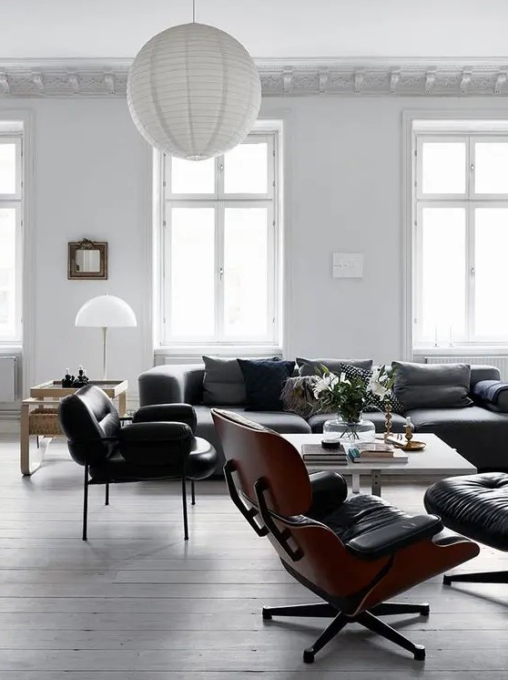 a black and white Scandinavian living room with plenty of natural light, black seating furniture, a white coffee table and a white paper lamp