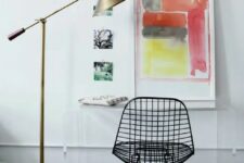 a bold space with a clear acrylic desk, a black Eames wire chair, bold artwork and a brass floor lamp is all cool