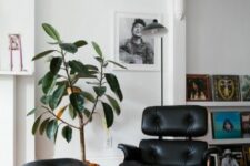 a bold space with bright artwork, a black Eames lounger, a potted plant is a lovely and cozy space to be in