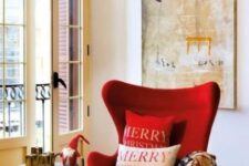 a bright and cozy nook with an artwork, a red Egg chair, a side table and some holiday decor