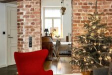 a chic Christmas space with a Christmas tree, a black sofa and a bold red Egg chair with an ottoman looks cool