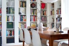 a cool dining space with white bookcases, a stained table and white Panton chairs and a Bubble pendant lamp