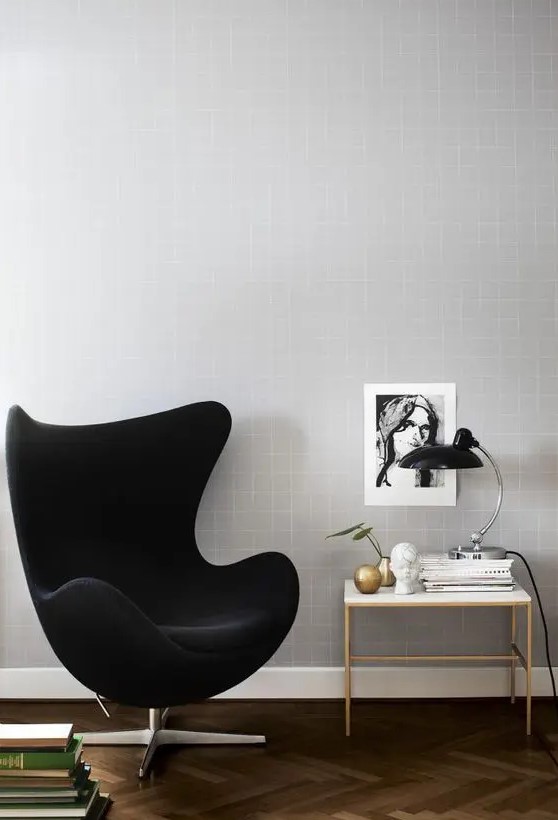 a cool nook with a black velvet Egg chair, a side table, books, decor and a table lamp is a chic and lovely space