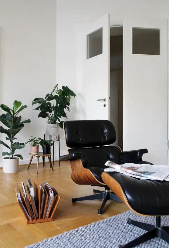 a cozy reading nook with a black Eames lounger and an ottoman, a magazine stand, potted plants is a lovely space