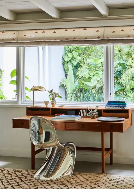 a home office with a vintage stained desk with drawers and a silver Panton chair that contrasts the desk a lot