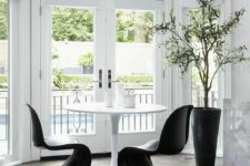 a laconic dining space with a round table and black Panton chairs, a potted plant and lovely views is amazing