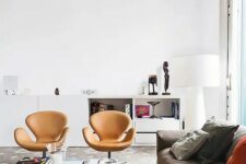 a lively living room with a taupe sofa and bold pillows, amber leather Swan chairs, a coffee table and a white storage unit