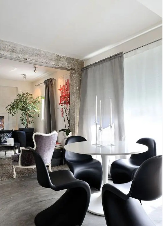 a minimal dining room with a round table, black Panton chairs and clear candleholders   who needs more for stylish dining