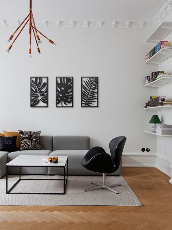 a modern living room with built-in shelves, a low grey sofa, a black leather Swan chair, a coffee table
