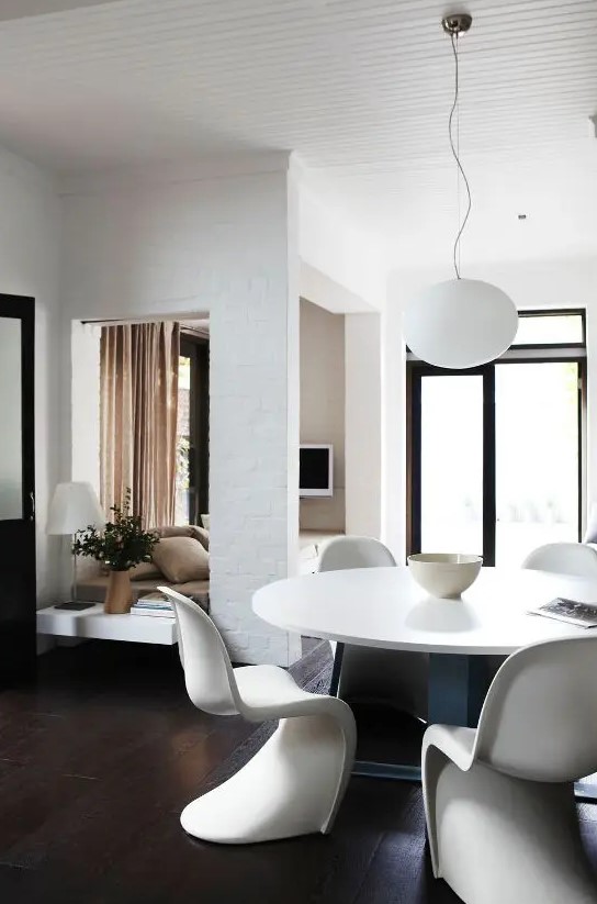a modern neutral dining space with a round table, white Panton chairs and a pendant lamp is cool and edgy