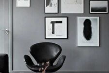 a monochromatic space with grey walls, a black and white gallery wall, a black sofa and a black Swan chair, a neutral rug