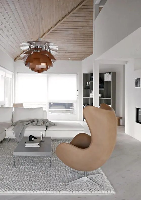 a neutral Scandinavian living room with a creamy corner sofa and a grey coffee table, a brown Egg chair and a pendant lamp