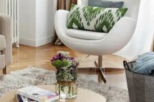 a neutral nook with a sofa, a white Egg chair with printed pillows, a basket, a fluffy rug and a low coffee table