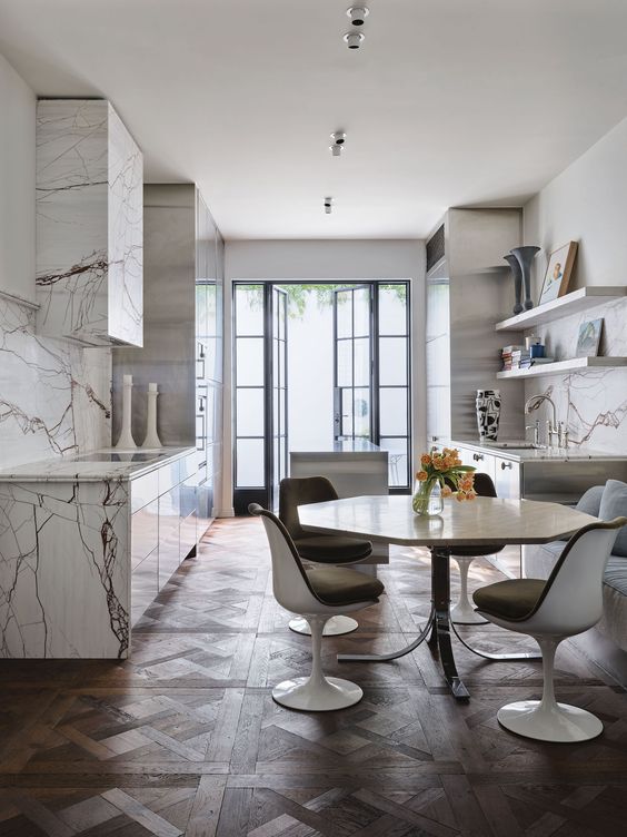 a refined eat-in kitchen with marble cabinets and a hood, open shelves, a geometric table and Tulip chairs