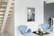 a small and stylish space with a black coffee table, light blue Swan chairs, a black and white artwork is a cool nook