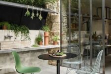 a small outdoor dining space with a black table, Eames chairs including wire ones and a planting station by their side