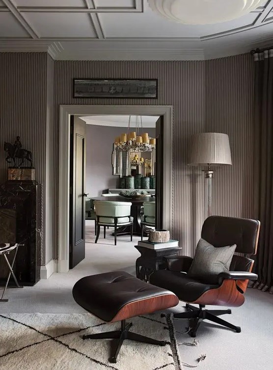 a sophisticated space with a black Eames lounger and ottoman, taupe walls, a chic floor lamp and a cool ceiling