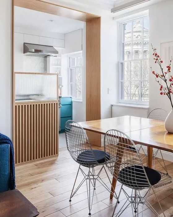 a stylish Scandinavian space with a kitchen flowing into a dining and living room, with a stained table and Eames wire chairs