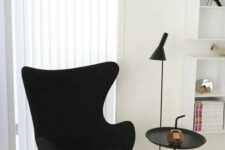 a stylish space with a black Egg chair, a side table, a floor lamp and some shelves is a cool and elegant space