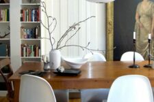 a vintage dining room with bookcases, a large artwork, a stained vintage table, stained wood chairs and white Panton ones