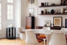 a vintage dining space with open shelves, an oval table, white Tulip chairs, some beautiful and sophisticated decor