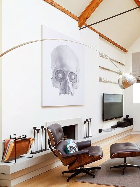 a whimsical living room with a fireplace, a TV, a bold artwork, a black Eames chair, some candleholders and a lamp
