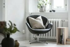 an airy Scandinavian space with a black leather Swan, potted plants, a crate as a side table and some artwork