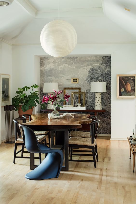 an eclectic dining room with a niche and a console table with lamps, a living edge table, wishbone and Panton chairs and some artwork