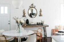 an eclectic dining room with a round table, mismatching chairs including Tulip ones, a jute rug, a wooden console table