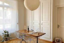 an elegant dining space with a built-in storage unit with paneled doors, a vintage dining table and Eames wire chairs plus a pendant lamp