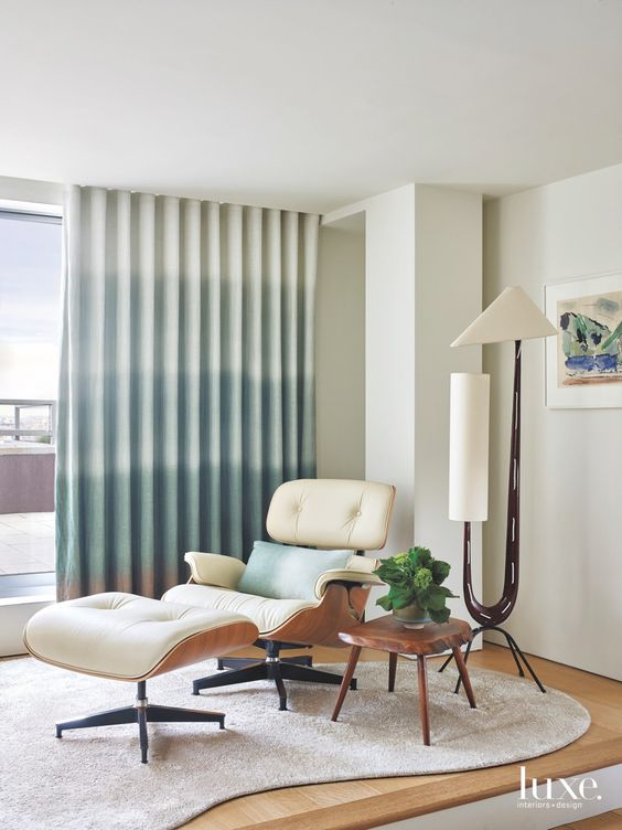 an elegant mid-century modern nook with a creamy Eames lounger, a tree slice side table, a floor lamp and a rug