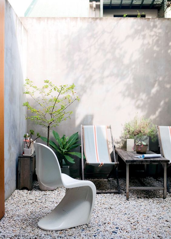 an outdoor space with hammock chairs and a Panton one, a stained table and some potted plants is cool
