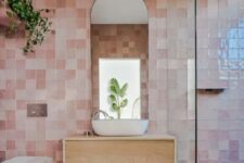 02 a beautiful bathroom clad with pink zellige tiles, a shower, a floating vanity, an arched mirror and some greenery