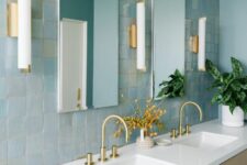 03 a blue bathroom clad with blue Zellige tiles, a large shared vanity with sinks, rectangular mirrors and sconces