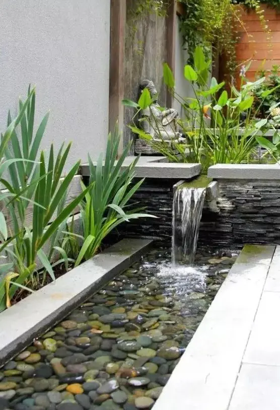 a chic modern waterfall going from a bowl with plants into a bowl with feathers and grasses around is a cool idea
