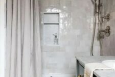 05 a chic contemporary bathroom clad with light grey and neutral zellige tiles, with a neutral shower curtain and a black vanity