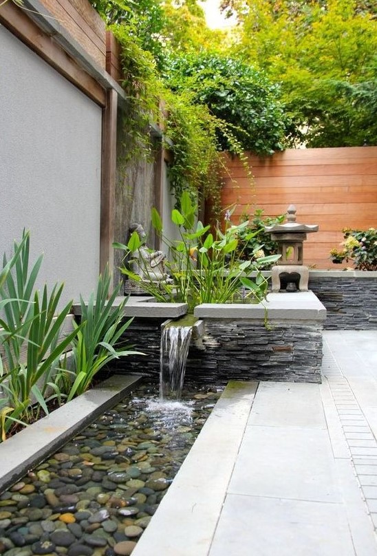 a modern and bold front yard waterfall clad with natural stone and tiles and with pebbles