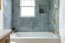 10 a modern bathroom with penny tiles and blue zellige ones around the tub, a timber vanity, gold and brass fixtures