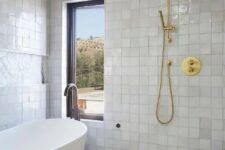 14 a neutral bathroom with white Zellige tiles and geometric ones, an oval tub and brass and gold fixtures