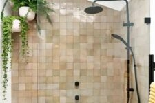 20 an attic shower space clad with blush and tan zellige tiles, with suspended potted plants and black fixtures for a modern feel
