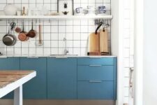 24 a catchy blue Scandinavian kitchen with only lower cabinets, a white square tile backsplash, an open shelf and a stained kitchen island