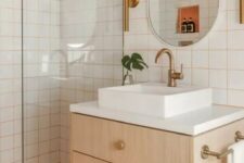 25 a bright modern bathroom with white square tiles with orange grout and orange penny tiles, a timber vanity, an oval mirror and brass fixtures