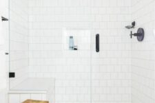 26 a catchy bathroom clad with white square and printed tiles, black fixtures for a more modern look and a wooden stool