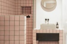 28 a catchy modern bathroom with pink square tiles, a terrazzo floor, a vanity clad with tiles and a round mirror