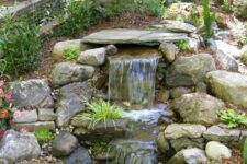30 a cool waterfall done with large rocks and some greenery and blooms around looks pretty Alpine and cool