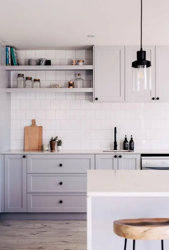 a grey Scandinavian kitchen with shaker cabinets, white stone countertops, white square tiles on the backsplash and pendant lamps