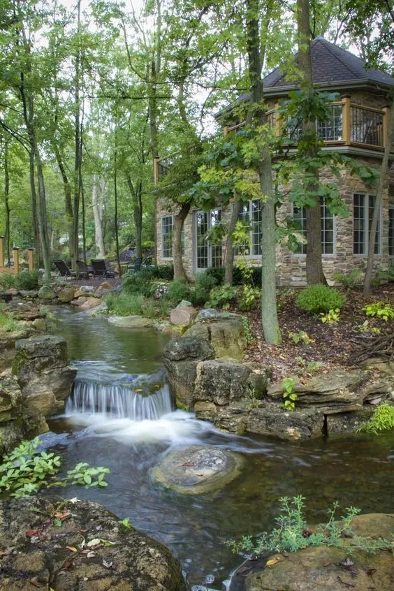 a garden with a large waterfall and larg rocks and greenery around looks super natural, as if it's a forest