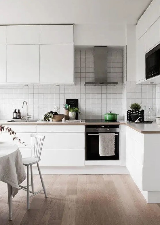 a minimal Scandinavian kitchen with sleek white cabinets, stone countertops and a white square tile backsplash