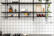 36 a neutral modern kitchen with stone countertops, a white square tile wall, a black shelving unit on the wall